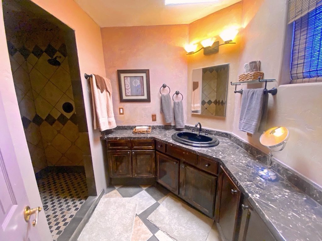 A bathroom with a sink, mirror and shower.